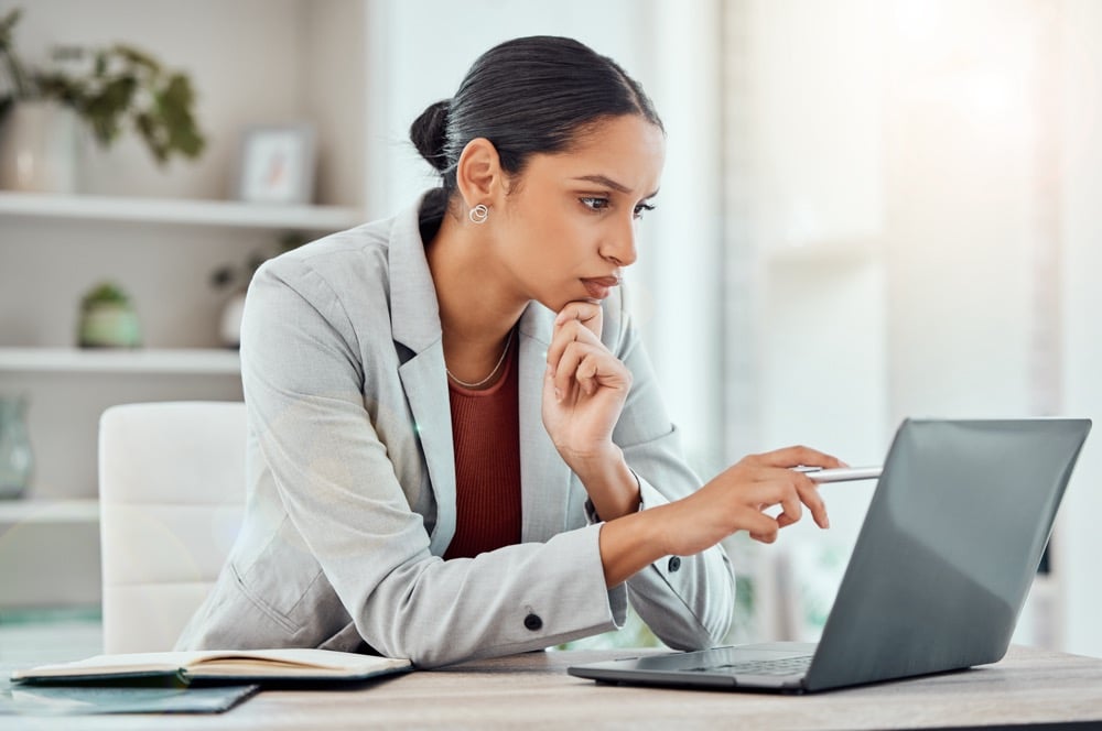 Serious, laptop and professional businesswoman sitting and reading a work email with a pen working from home. Business, computer and focused female lawyer in modern office preparing for a case.